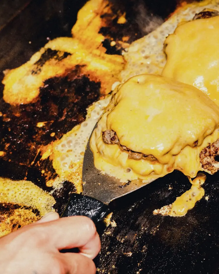 American cheese melting over smashed patties on the griddle