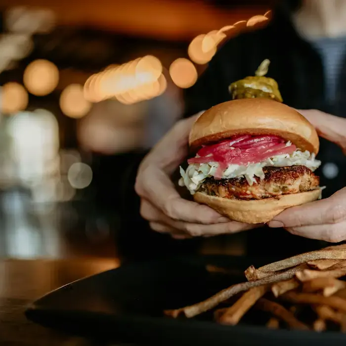 A finished burger held in two hands, ready to eat